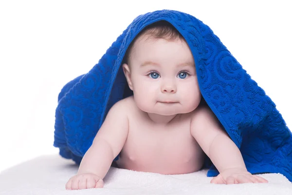 Bebê com grandes olhos azuis olhando para a câmera sob toalha azul / branco — Fotografia de Stock