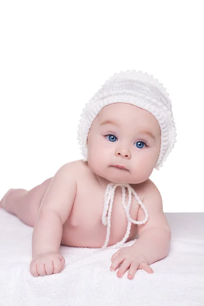 Baby child lying down on blanket wearing white hat, isolated — Stock Photo, Image