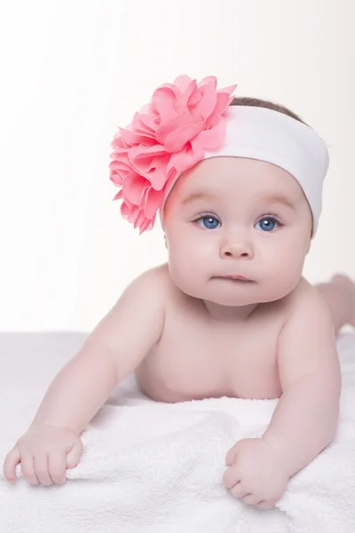 Cute little baby girl with pink bow flower on her head — Stock Photo, Image