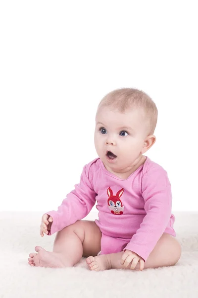 Bebê sentado e olhando surpreso para o lado — Fotografia de Stock