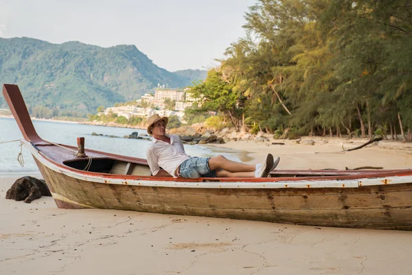 Sahilde bir teknede yatan adam