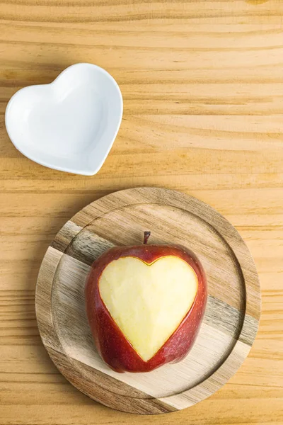 Elmaya kazınmış kalbin yakın çekimi ve küçük beyaz kalp şeklinde bir tabak.