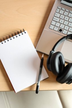 Ömür boyu öğrenim ve çevrimiçi eğitimi temsil eden bir ev eğitim masasının düz açısını kapatın. Büyük kopya alanı, not defteri, kalem, dizüstü bilgisayar klavyesi ve kulaklığı olan boş bir kağıt..