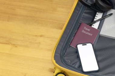 Akıllı telefon, pasaport, defter ve kulaklıklarla dolu açık bavulun çam ağacından yapılmış yatay görüntüsü. Kopya alanı ile en düşük yaz seyahati kavramı.