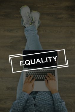 Genç adam dizüstü bilgisayarla yerde oturuyor.