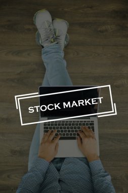 Genç adam dizüstü bilgisayarla yerde oturuyor.