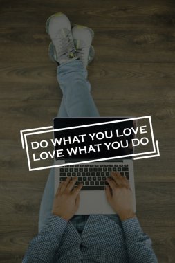 Genç adam dizüstü bilgisayarla yerde oturuyor.