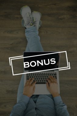 Genç adam dizüstü bilgisayarla yerde oturuyor.