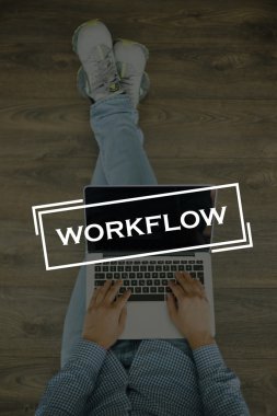 Genç adam dizüstü bilgisayarla yerde oturuyor.