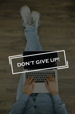 Genç adam dizüstü bilgisayarla yerde oturuyor.