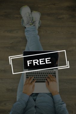 Genç adam dizüstü bilgisayarla yerde oturuyor.