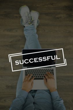 Genç adam dizüstü bilgisayarla yerde oturuyor.