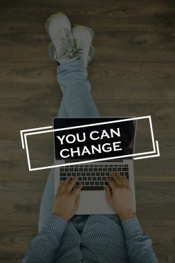 Genç adam dizüstü bilgisayarla yerde oturuyor.