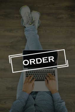 Genç adam dizüstü bilgisayarla yerde oturuyor.