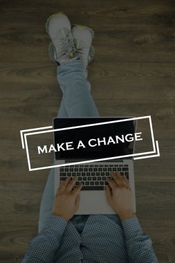 Genç adam dizüstü bilgisayarla yerde oturuyor.