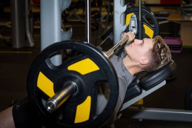 Genç sporcular spor salonunda halterle antrenman yapıyor.