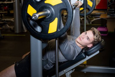 Genç sporcular spor salonunda halterle antrenman yapıyor.