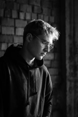 Pembe sarı saçlı, gözlüklü ve siyah kapüşonlu genç modellerin portresi. Kışın karlı havada, ormanın yanındaki tarlada duruyordu.