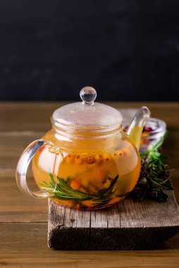 Lezzetli ve sıcak çay Buckthorn Denizi 'nden ve Taze Rosemary Cozy Sıcak İçecek Odunu Ahşap Arka plan ve Tahta Tepsi