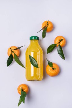 Olgun mandalinalı bir şişe taze mandalina suyu. Sağlıklı Detox İçeceği Üst Görünüm Mavi Arkaplan