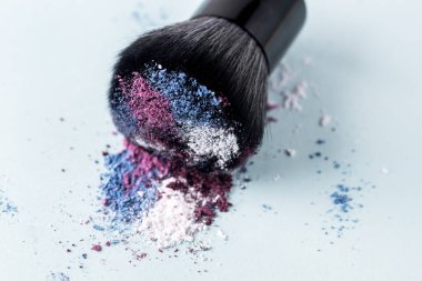 Açık Mavi Arkaplanda Çok Renkli Toz ile Makyaj Fırçası
