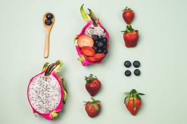 Ekzotik Meyve Salatası ile arka plan Yarım Ejderha Meyvesi ve Çiğ Çilek ve Yaban mersinli Açık Yeşil Arka plan Üst Görünüm Yatay Sağlıklı Diyet Tatlısı