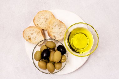 Zeytinyağı dilimli cam kaseler ve beyaz ahşap tepside yeşil zeytinler Gri Arka plan Üst Görünümü