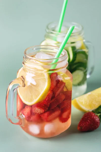 ガラス瓶の冷たい夏のドリンクの様々なキュウリレモンとストロベリー健康飲料緑の背景とデトックス水を注入 — ストック写真
