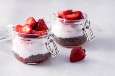 Çilekli Chia Tohum Pudingi ve Cam Kavanozlarda Hindistan cevizi Sütü Sağlıklı Çiğ Vejetaryen Tatlısı