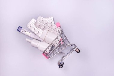 Tıbbi Termometre Burun Spreyi ve Haplı Küçük Alışveriş Aracı Mavi Arka plan Gribi veya Covid 19 Alışveriş Konsepti Üst Görüş