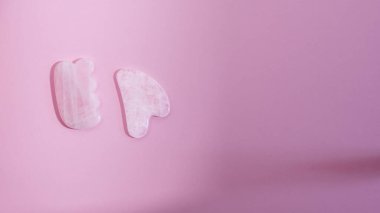 Yüz ve Vücut Bakımı Yatay Yatay Spa Minimum Konsepti için Gölgeler Pembe Yeşim Taşı ile Pembe Arkaplanda Gua Sha Masajcısı