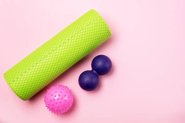 Foam Roller and Ball Roller Fitness Equipment Pink Background Myofascial Release MFR Female Hand Holds a Roller Relax and Fitness Concept