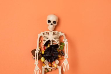 Cadılar Bayramı İskeleti ve Turuncu Arkaplanda Şeker ve Şekerler Cadılar Bayramı Arka planı veya Card Top View