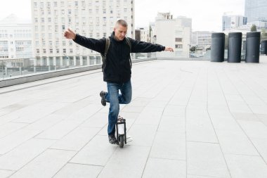 Şehir caddesinde tek tekerlekli bisiklete binen adam. Taşınabilir bireysel ulaşım aracı. Electric mono-wheel kullanan adam hızla EUC 'ye gidiyor.