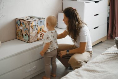 Bebeklere oyun oynamayı öğreten, el koordinasyonu ve duyusal beceriler geliştiren, evde ebeveynlik ve çocuk eğitimi veren genç bir kadın.