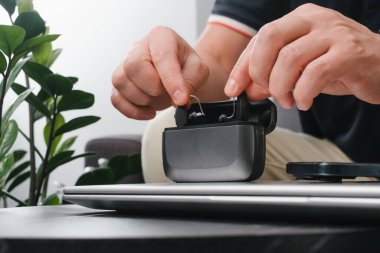 Modern işitme cihazları, akıllı telefon ve şarj çantaları şık bir ofis masasında, iş için hazırlanmış cihazlarla birlikte. İş ortamı, ulaşılabilirlik ve profesyonel yaşam tarzı. Adam kulaklık kullanıyor. 