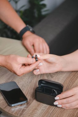 Küçük ölçekli işitme cihazlarını elinde tutan el kameraları. Rehabilitasyon ofisi