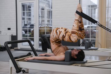 40 'larında olgun bir kadın, çekirdek dayanıklılık ve esneklik için ayakta denge egzersizinde ileri derecede pilates yapıyor. Düşük etkili düşünceli hareket yoluyla dengeyi geliştiren kadın