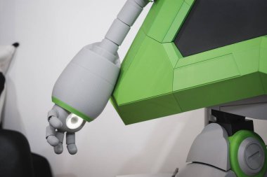 Modern teknoloji çalışma alanındaki bilgisayar masasının üstünde eklemli parmakları olan yeşil ve gri insansı robot koluna yakın çekim
