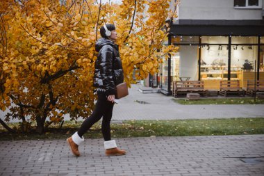 Kulaklık takan kadın, sonbahar şehir avlusunda bilinçli olarak yürüyor, müzik dinliyor ve akıl sağlığını koruyor..