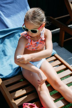 Yaz tatilinde koluna koruyucu güneş kremi süren sevimli bir çocuk. Küçük kız güneşlenmek için güneş kremi kullanıyor. Dışarısı ve cilt güvenliği için..