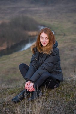 Tepede oturan çekici genç kadın.