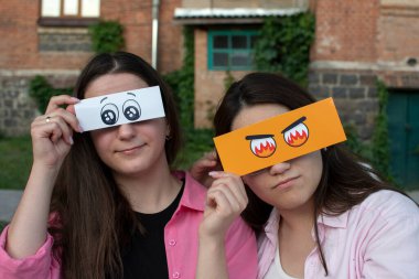 Komik, kağıttan gözlü iki genç kadının portresi.