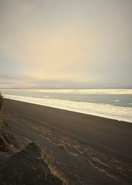 İzlanda 'da güzel bir gün batımı olan kumlu bir sahilin dikey görüntüsü.