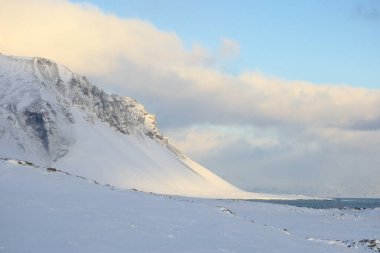 İzlanda sahilinde karla kaplı bir dağ manzarası