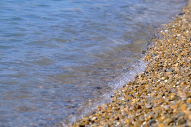 Mavi deniz dalgalı çakıl taşı plajı