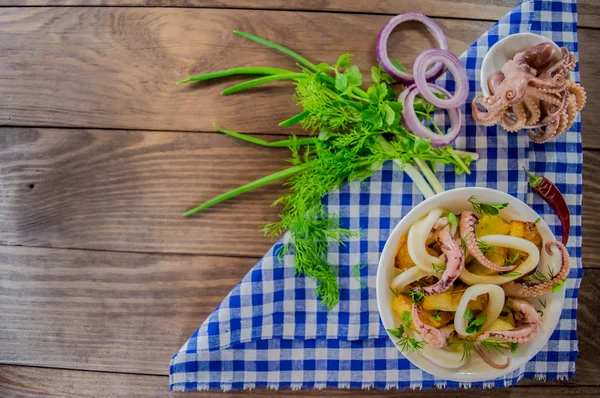 Siapkan cincin cumi-cumi segar dan tentakel gurita dengan kentang rebus dan hijau di pedesaan — Stok Foto