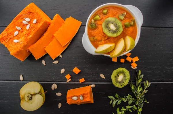 Purée de citrouille aux fruits sur fond de bois noir. Vue du dessus — Photo