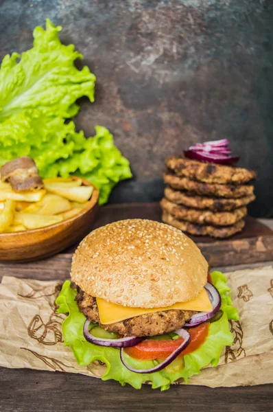 Slaninový burger s hovězí plackou na dřevěném stole — Stock fotografie