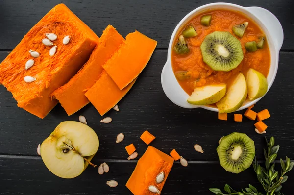 Purée de citrouille aux fruits sur fond de bois noir. Vue du dessus — Photo